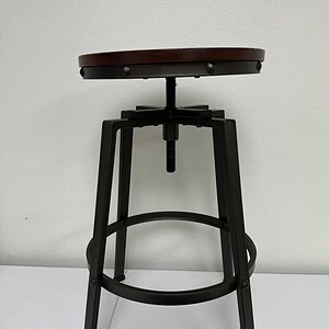 Style stool with wooden seat and adjustable height.