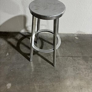 Metal stool with round seat and minimalist design.