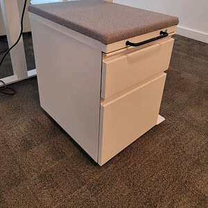 Herman Miller white mobile pedestal with grey cushion top for office storage.
