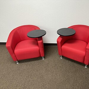 Red lounge chairs with attached tablet tables for modern office or lounge spaces.