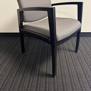 Modern grey executive chair with black wooden frame and armrests.