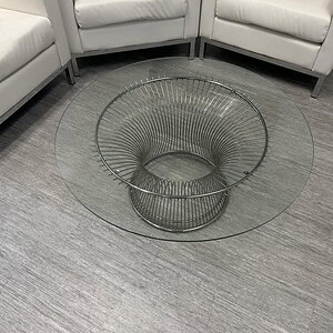 Modern glass top coffee table with a stylish steel wire base, perfect for contemporary living rooms.