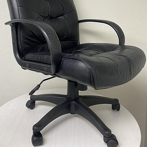 Office black vinyl executive chair with armrests and adjustable height.