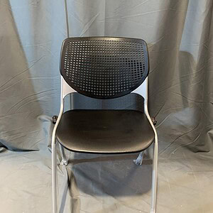 Modern black and silver stacking chair with perforated backrest.