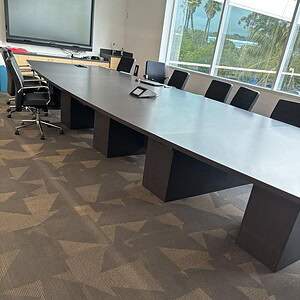 Modern boat-shaped conference table in a bright, professional office setting.
