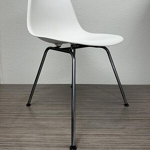 Modern Eames molded plastic chair with steel frame in white finish.