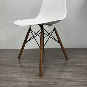 Modern Eames style chair with wooden legs and molded plastic seat.