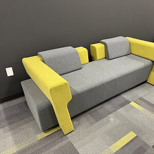Green and grey modern sofa with open environment design for office or lounge areas.