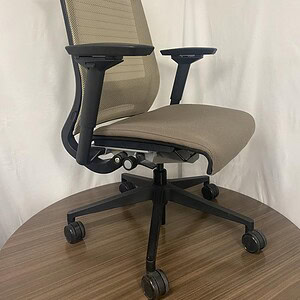 Office ergonomic chair with tan fabric and black mesh backrest for comfort and support.