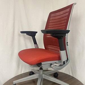 Ergonomic red and silver office chair with mesh back and adjustable features.