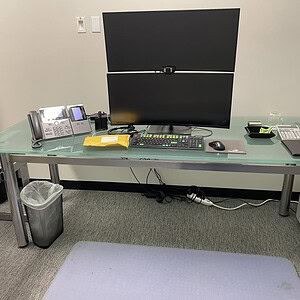 Glass conference table with dual monitors and office equipment.