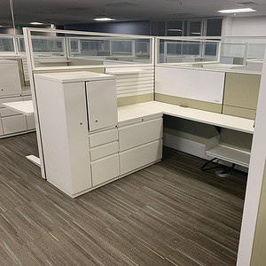 Modern office cubicle with glass partitions and beige fabric panels.