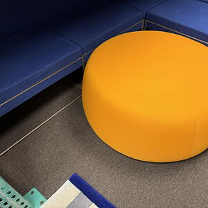 Orange plush ottoman for modern lounge spaces.