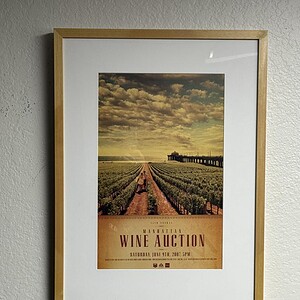 Framed poster for Manhattan Wine Auction event with vineyard scene and sunset.