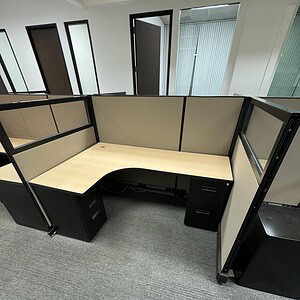 Office cubicle with neutral tones and glass panels for modern work environments.