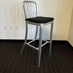 Metal stool with black cushioned seat, ideal for contemporary home or commercial spaces.