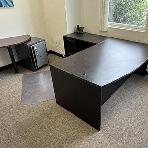 Office desk with L-shape design, black finish, ideal for workspace organization.