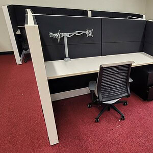 Office cubicle with white trim, black tiles, and ergonomic chair for workspace efficiency.