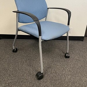 Light blue office chair with casters, ergonomic design, ideal for workspaces and conference rooms.