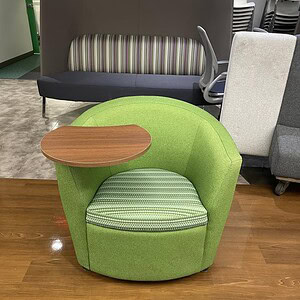 Green soft chair with integrated swivel desk for versatile workspace comfort.