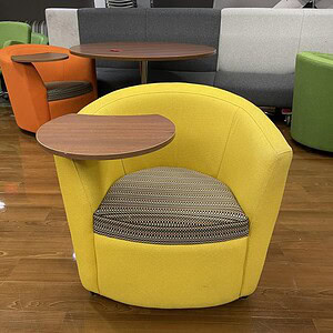 Yellow soft chair with integrated swivel desk for versatile workspace comfort.
