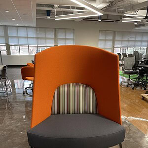 Stylish orange high back chair with privacy screen for modern office environments.