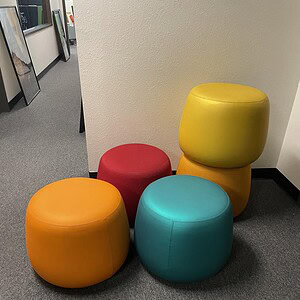 Vibrant, plush ottomans in yellow, red, orange, and teal for versatile seating and decor.