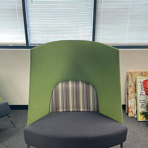 Green high back lounge sofa with a striped interior and black base, ideal for contemporary office or.