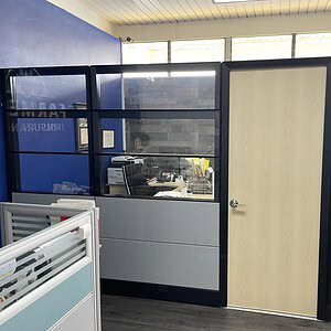 Private office with triple glass walls and wood door in modern workspace setting.