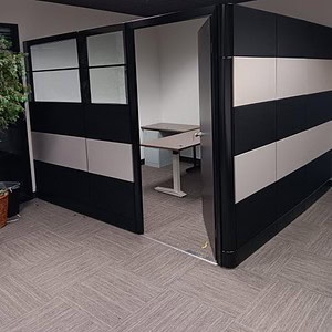 Black and silver office cubicle with glass panels and a desk for workspace privacy.