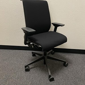 Modern black office chair with adjustable armrests and ergonomic design.