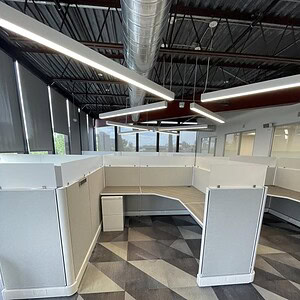 Modern grey and white cubicle with glass panels for office privacy and style.