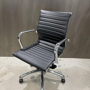 Black Herman Miller Eames style office chair with chrome armrests and adjustable height.