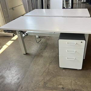 Height adjustable white Poppin benching for modern office spaces.