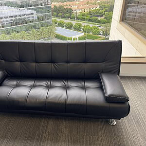 Black vinyl sofa with foldable futon for versatile seating and sleeping solutions. Perfect for moder.