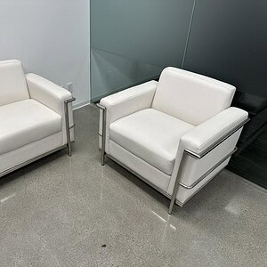 White leather armchairs with sleek chrome frames for contemporary office or lounge spaces.
