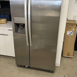 Whirlpool WRS322FDAM04 steel refrigerator with side-by-side doors and water dispenser.