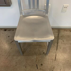 Emeco Silver dining chair with metal frame and cushioned seat.