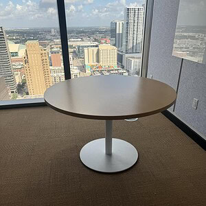 Round table with a maple top and white base, ideal for office or conference rooms.