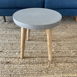 Stone finish round coffee table with wooden legs, perfect for contemporary home decor.