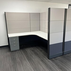 Office cubicle with black and silver panels, includes storage drawers and privacy panels.