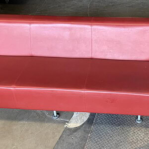 Red leather sofa with sleek design, ideal for contemporary work environments and lounge areas.