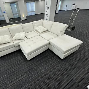 White leather L-shaped sofa with matching ottoman for modern living rooms.