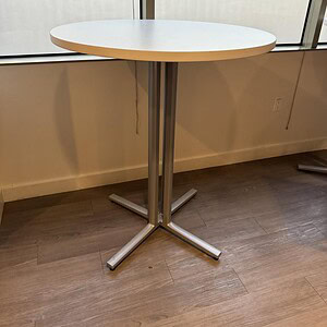 Modern Herman Miller bar height table with sleek metal base and round white top.