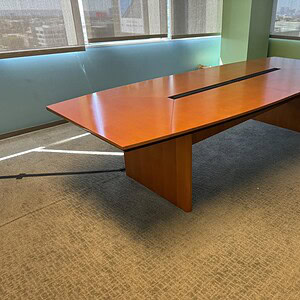 Conference table with honey veneer finish and integrated power outlets.