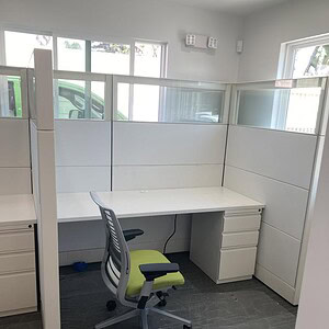 Office cubicle with white panels, ergonomic chair, and workspace for productivity.