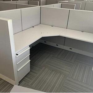 Modern office cubicle with white panels and storage drawers, ideal for workspace organization.