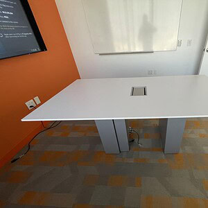 Powered white and silver conference table with built-in electrical outlets, ideal for modern office.