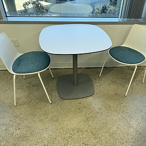 Steelcase Coalesse 30-inch rounded steel table base with two modern chairs.