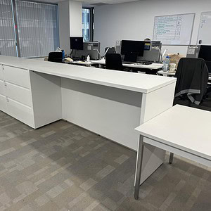 Modern office workspace featuring white storage units and desks in a professional environment.